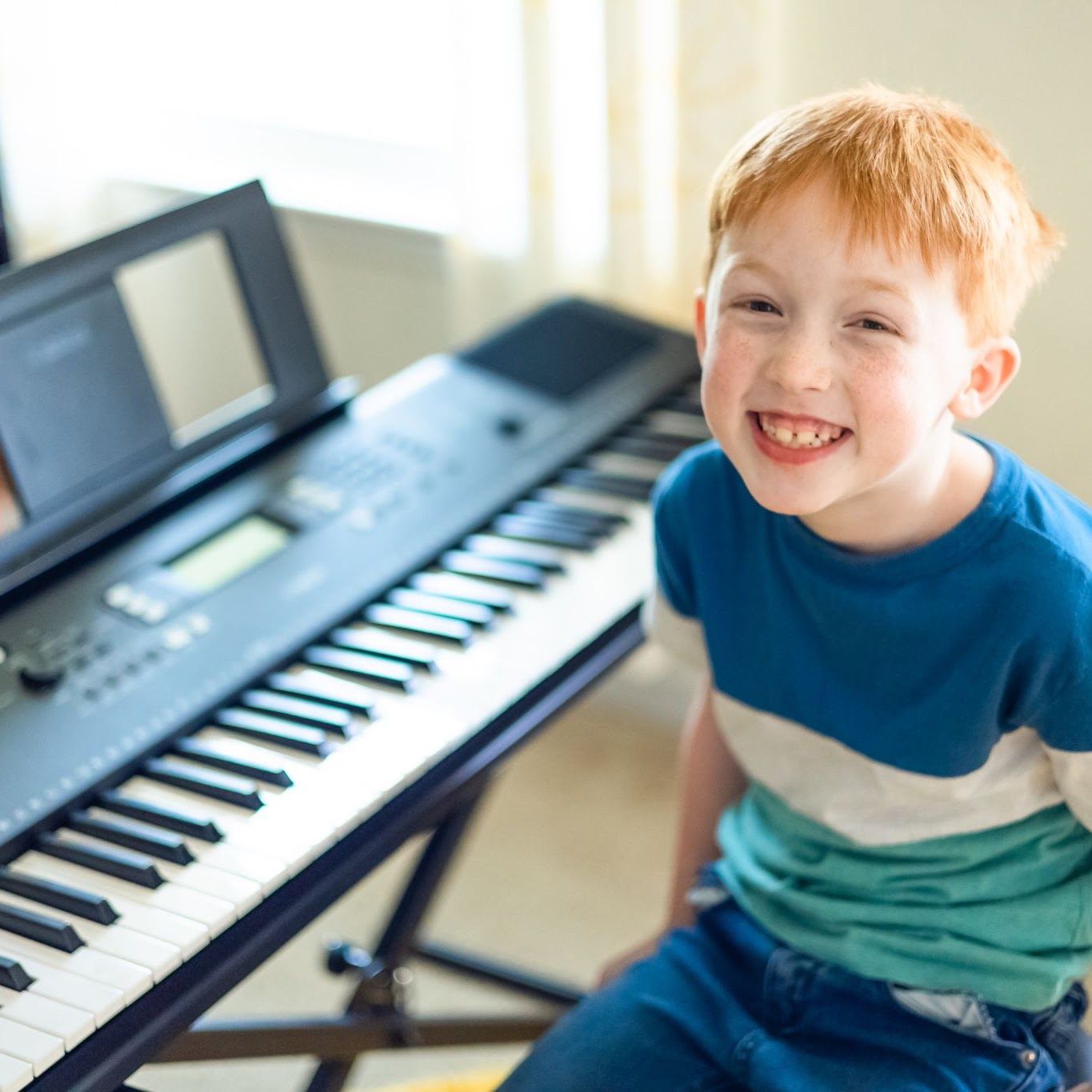 A young boy laughing at the keyboard